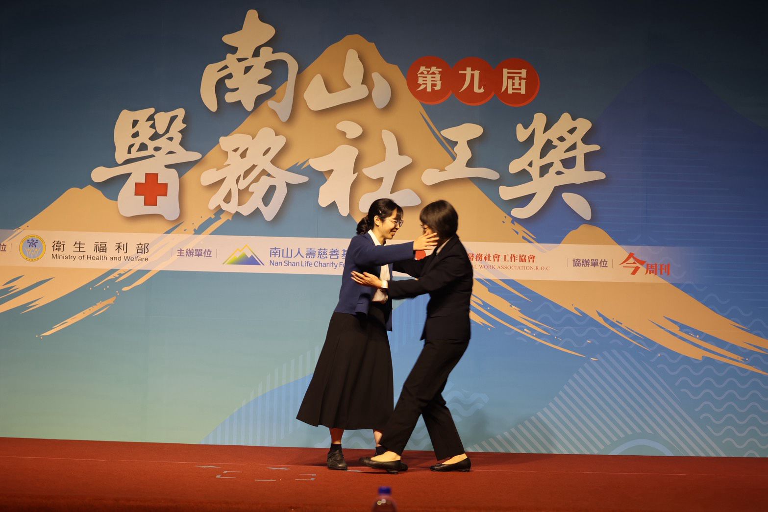 花蓮慈濟醫院醫務祕書吳雅汝醫師擔任頒獎介紹人，他感謝卓依蒨醫務社工師，在高壓的重症醫療歷程裡，不但接住了病人和家屬，也接住了所有醫護同仁。兩人緊緊擁抱。
