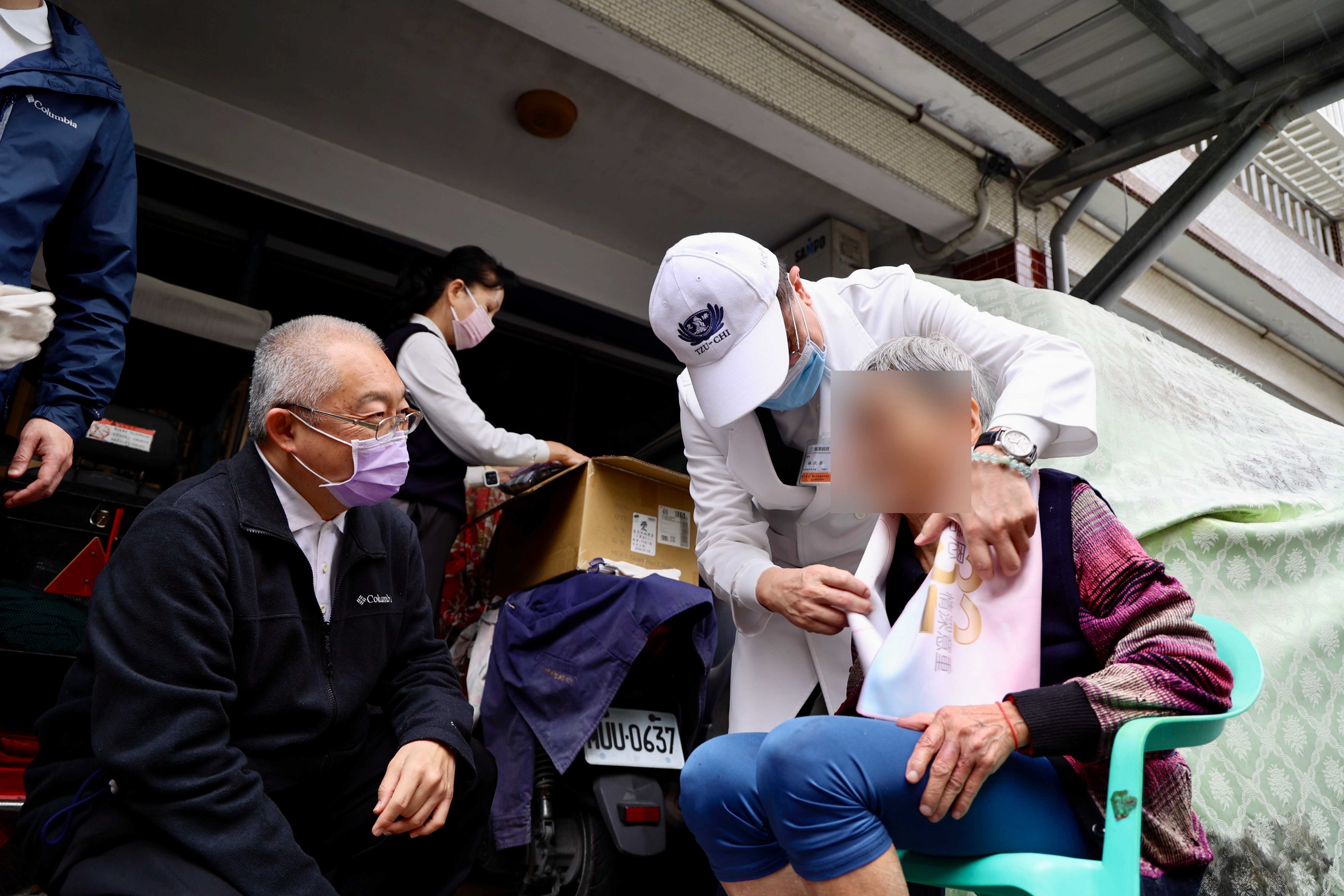 花蓮慈院林欣榮院長與特殊需求者牙科主任李彞邦為阿嬤送上背心新衣與圍巾,祝福溫暖過新年
