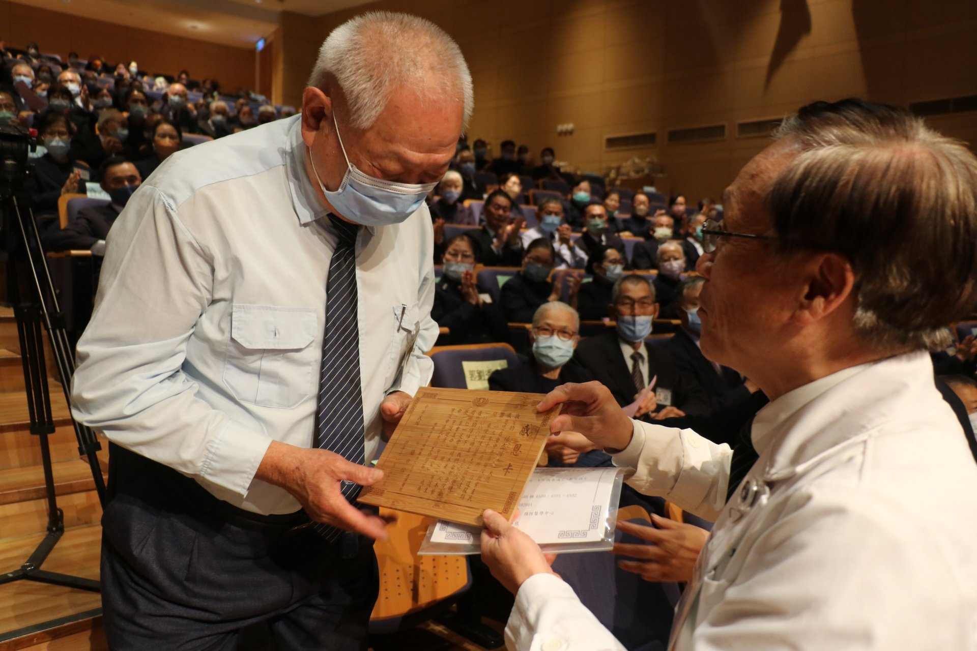 簡守信院長(右)表揚服務時數突破一萬小時的楊立川(左)。楊立川雖年邁拄著拐杖仍堅持服務,精神令人感佩。