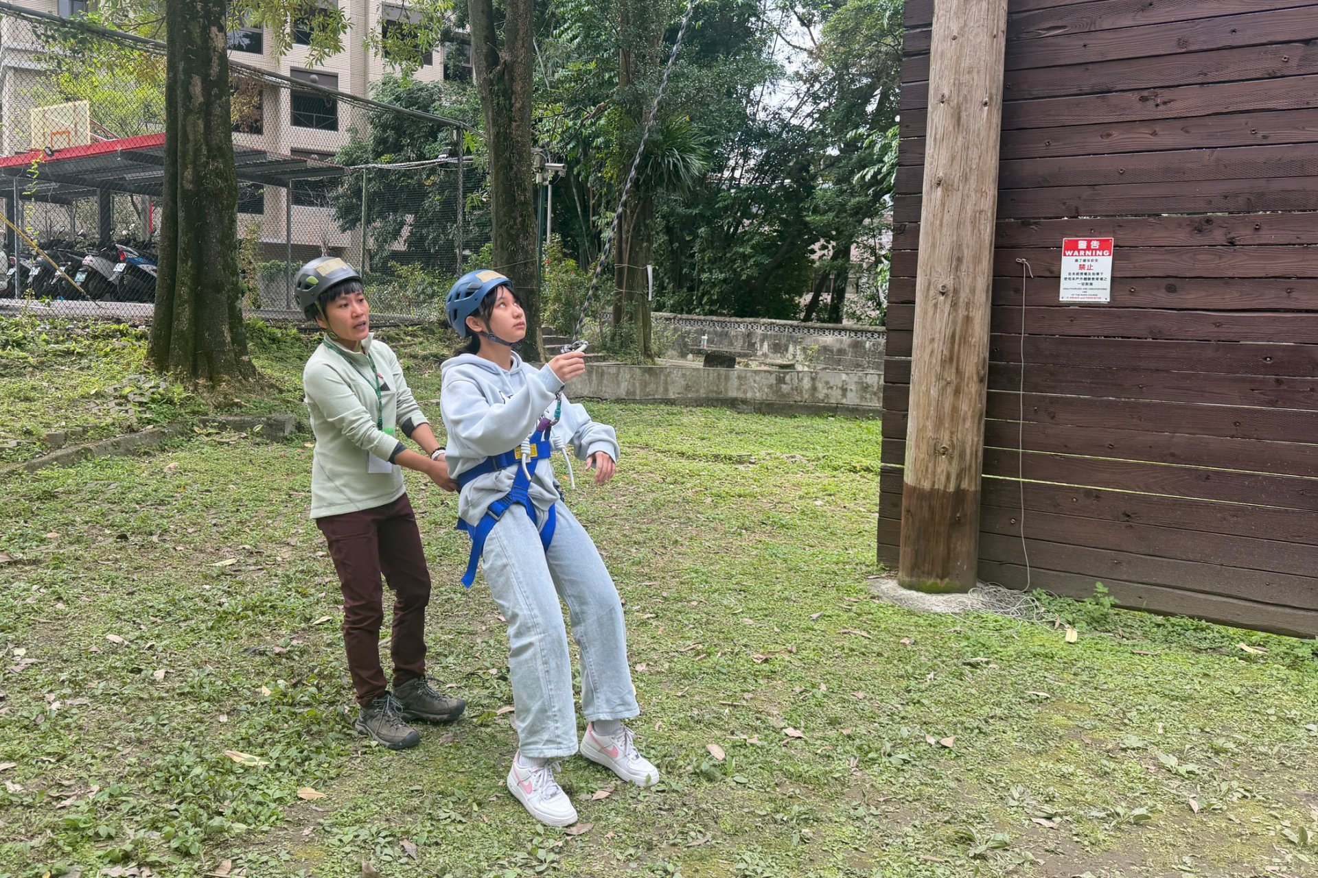 青少年學員在教練指導下進行高空攀爬的預備練習