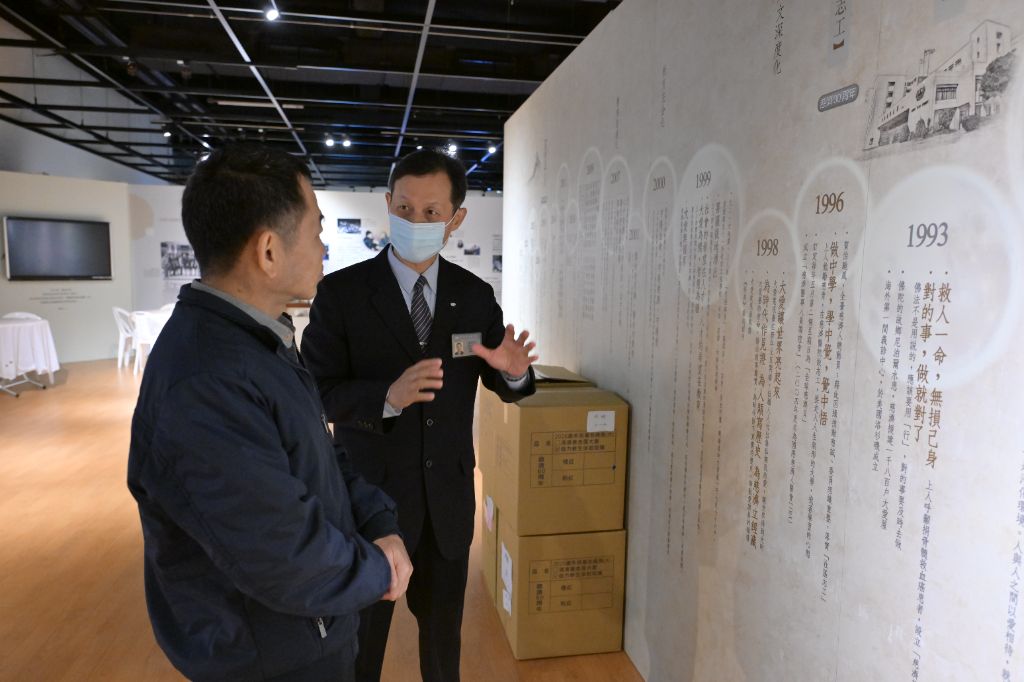 志工駱怡君(右)引領許先生到展覽區,了解慈濟五毛錢的力量發揮到全世界。希望每一個人從新年開始,可以發揮良能。