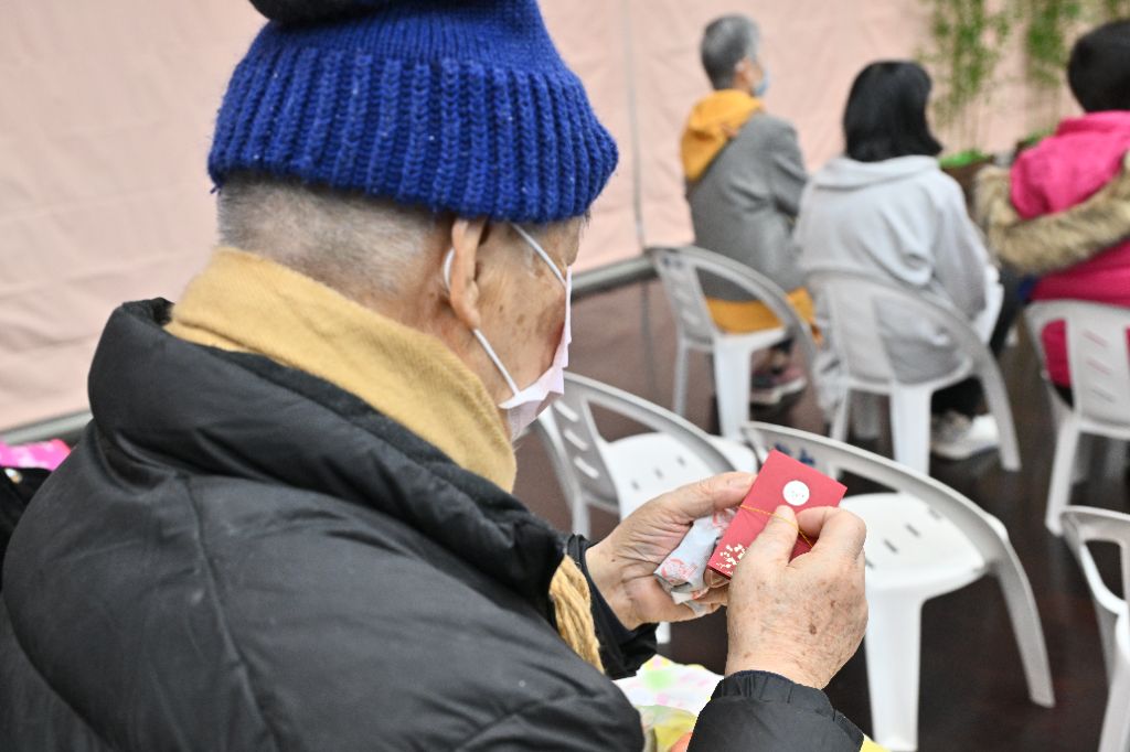 靜思精舍常住師父走到座位區,為養護中心的長者祝福,收到師父結緣的福慧紅包,長者珍惜的將它握在手中仔細端詳。