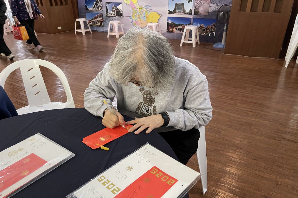 六十七歲徐碧娥是樂齡成長班學員,十分喜愛禪繞畫,今年首次設置禪繞畫攤位,她特地為自己繪製一個專屬於2026年的禪繞畫紅包,對照樣本一筆一畫,格外專注投入。