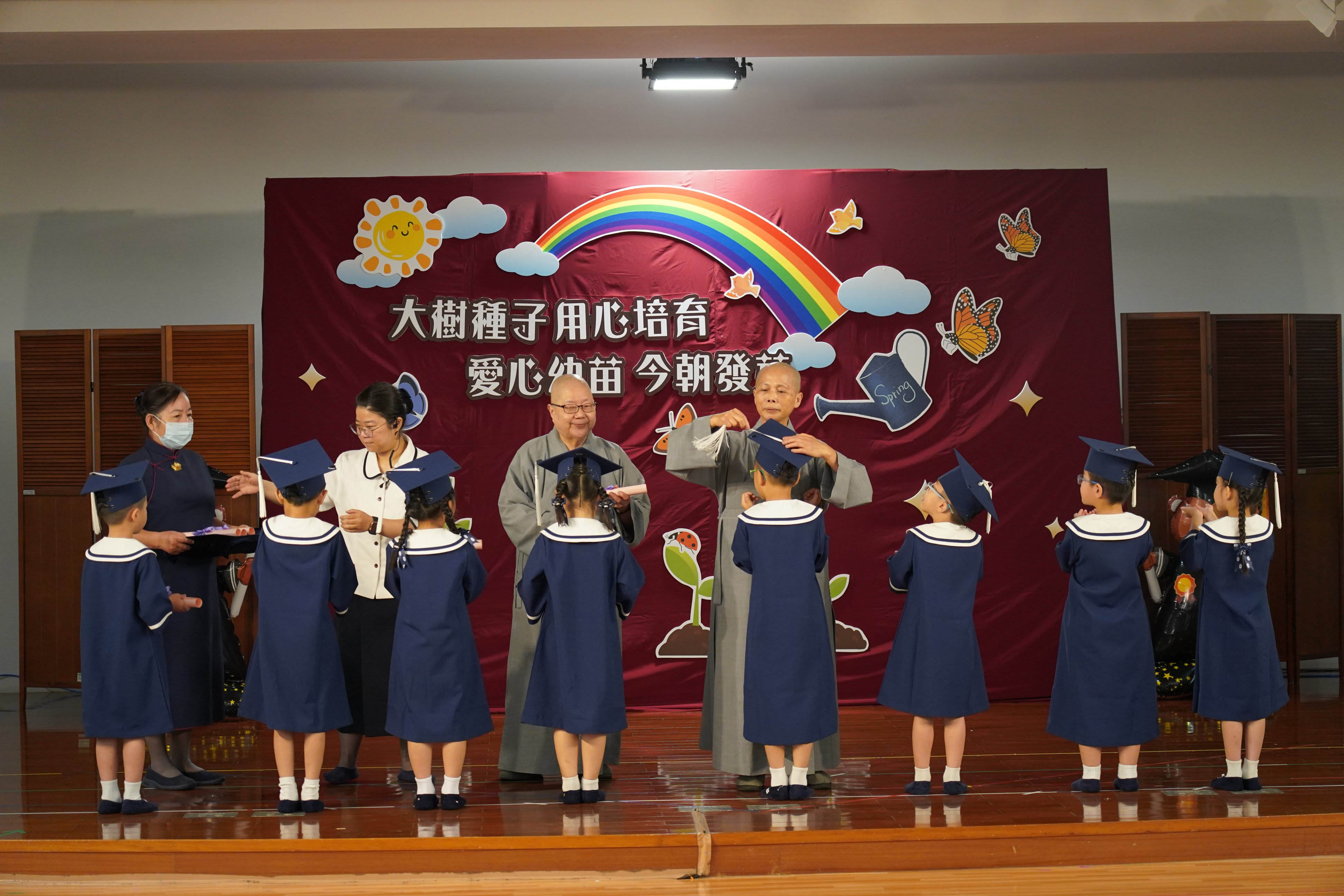靜思精舍德旭師父（後左）與德守師父（後右）為畢業生撥穗、頒發畢業證書，祝福孩子在人生旅程中持續茁壯成長。