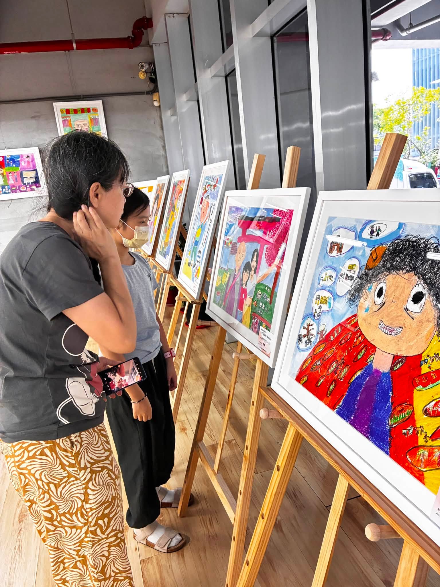 民眾駐足欣賞學生畫作,細細品味每幅作品背後的家庭故事,在觀展過程中感受藝術帶來的感動與跨世代交流的美好。