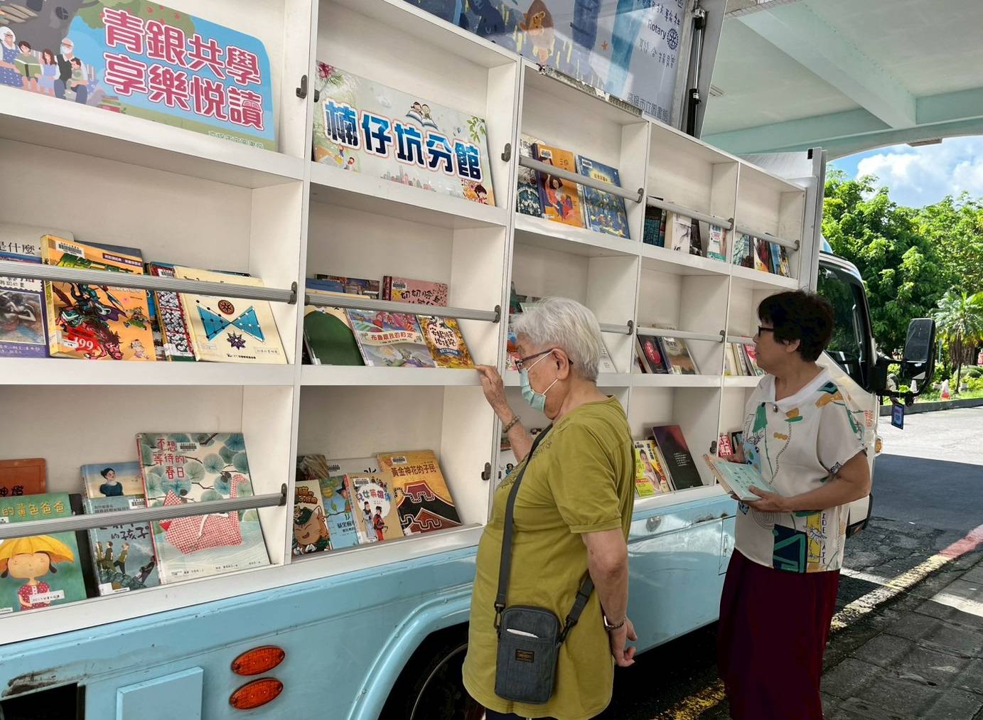 高市圖行動書車開進高雄榮家園區,長輩挑選喜愛的讀物,享受夏日閱讀時光。