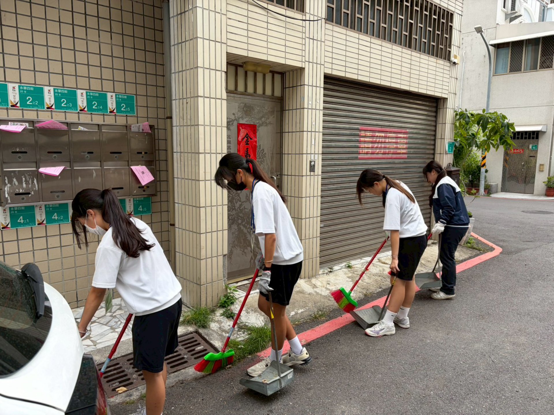 同學們排成一列,細心打掃社區住家門前。