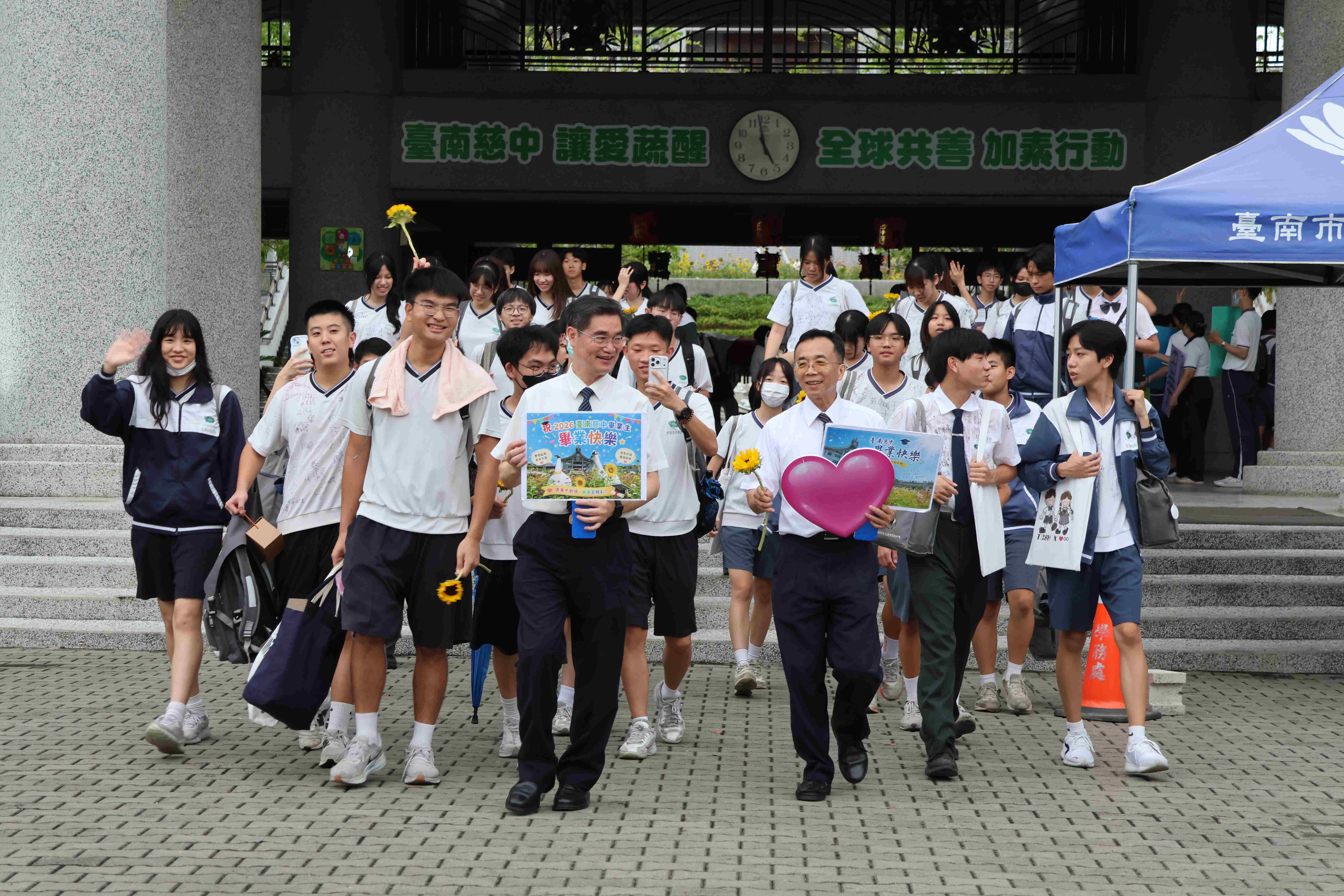 校長與執行長辦公室簡東源主任帶領校園巡禮的畢業生們走出校園，迎向未來。