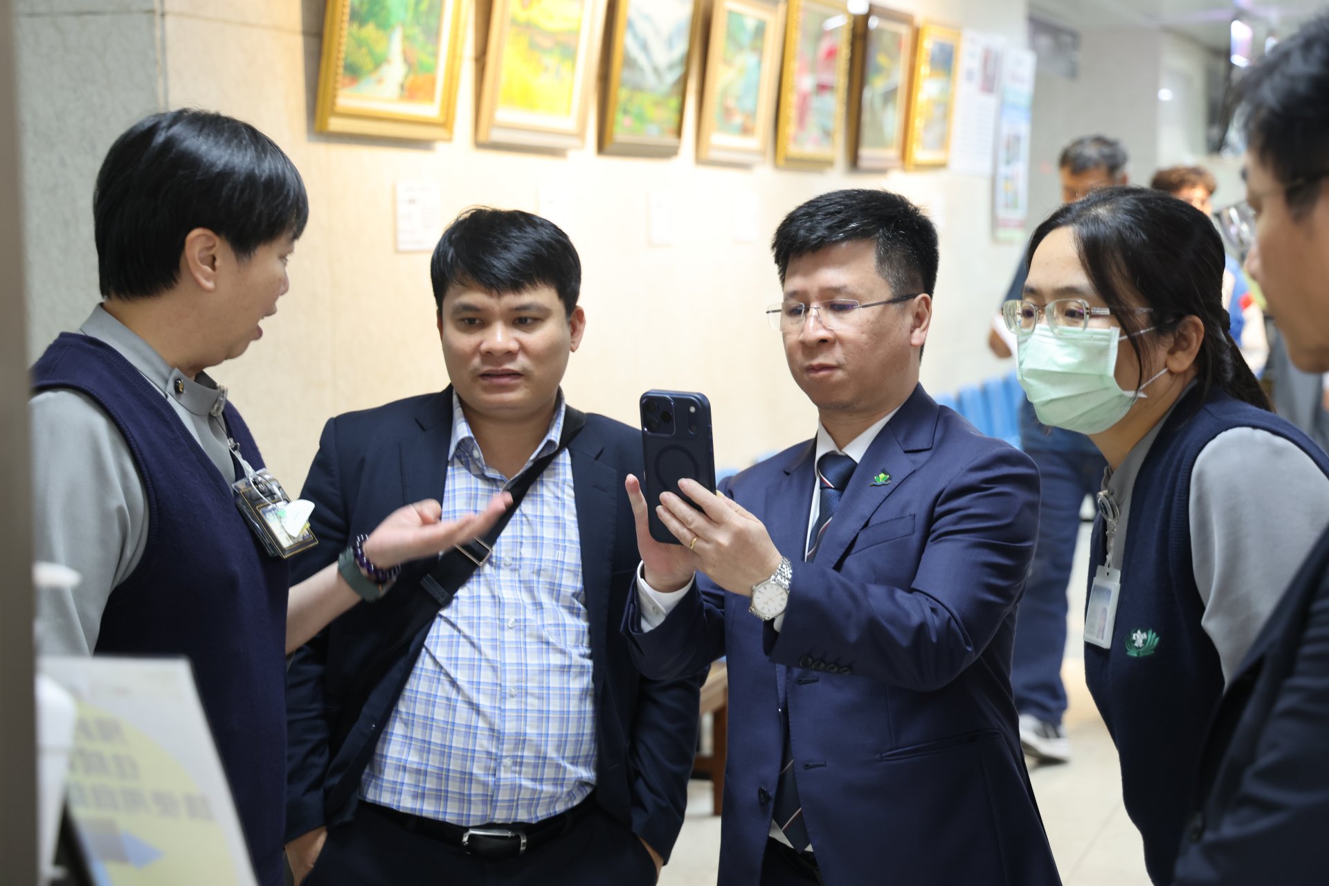 花蓮慈院醫事室張菁育主任(左)介紹入出院自動系統,來自越南的高越松副院長認真的以手機記錄。