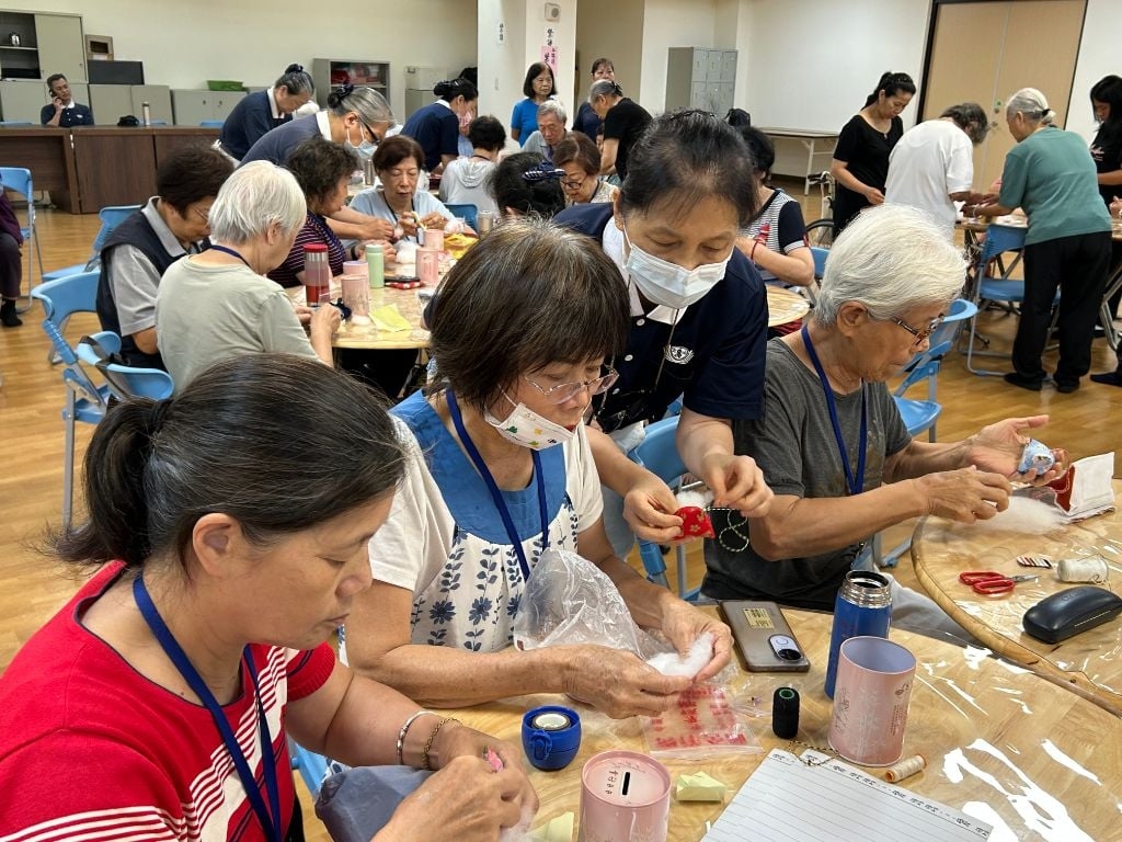 巧藝坊吳珍徵老師(中藍衣)感恩學員們,在端午佳節前夕陪伴長輩們一起動手做香包。她感性地說:「手做香包活動的氛圍,猶如兒女與長輩溫馨互動,很令人感動。這項服務不僅豐富了長者的生活,也傳遞溫暖的祝福與感恩之情。」
