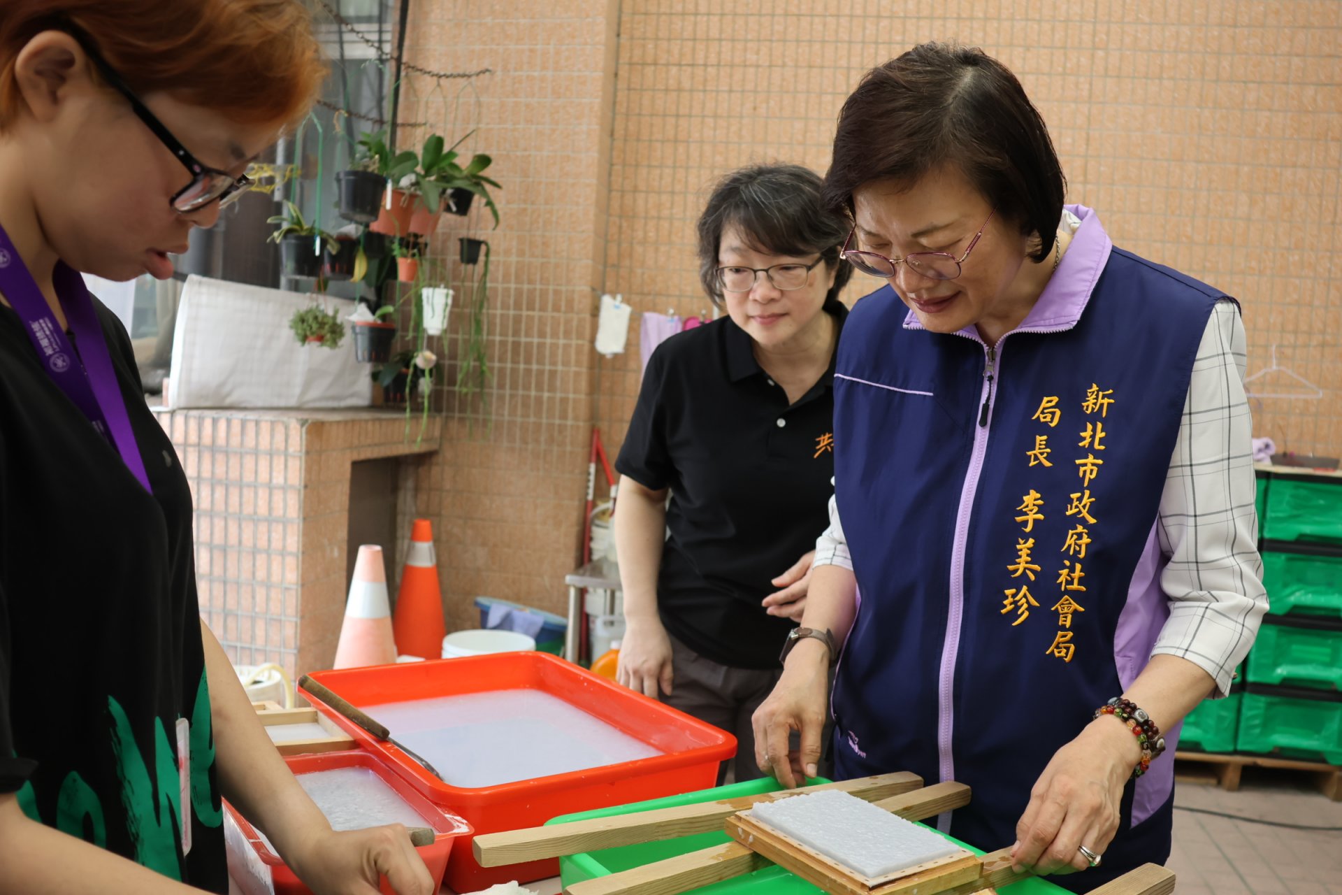 新北市社會局局長李美珍在服務對象的引導下，體驗手作手抄紙。