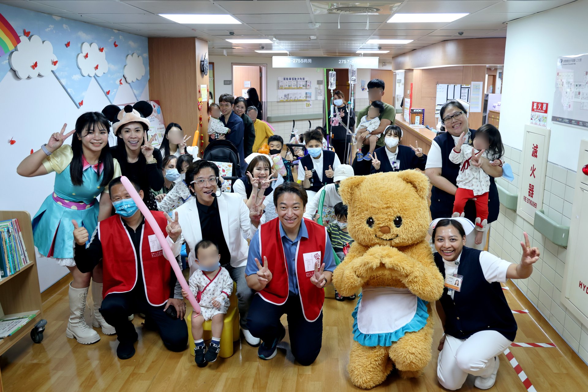 3月30日,愛花蓮文化藝術基金會董事長暨花蓮縣議員魏嘉賢(前排右三穿著紅背心者),再度攜手藝人雷恩叔叔(前排右四穿著白西裝者)、漢堡姊姊(第二排左一身穿藍衣者)以及人偶「漢堡熊」,陪伴住院的小勇士們提前慶祝兒童節。