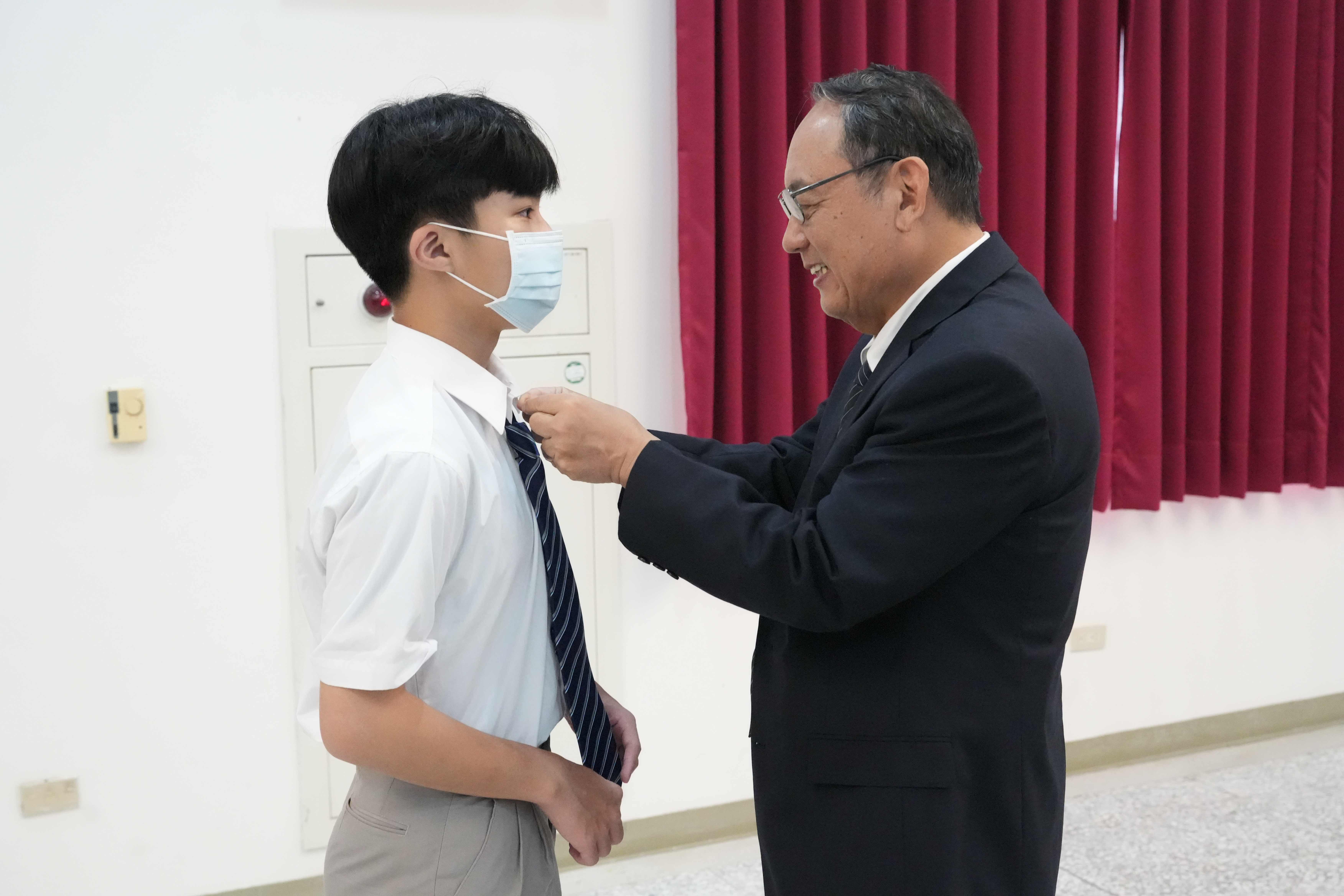 資深副校長戴昌賢幫學生打領帶